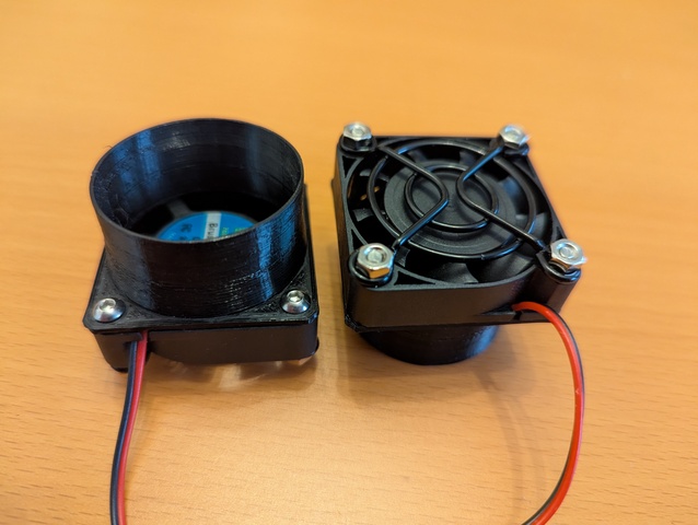 Two 40 mm fans with the holder and a fan guard attached, one seen with nozzle, the other with back side on top.